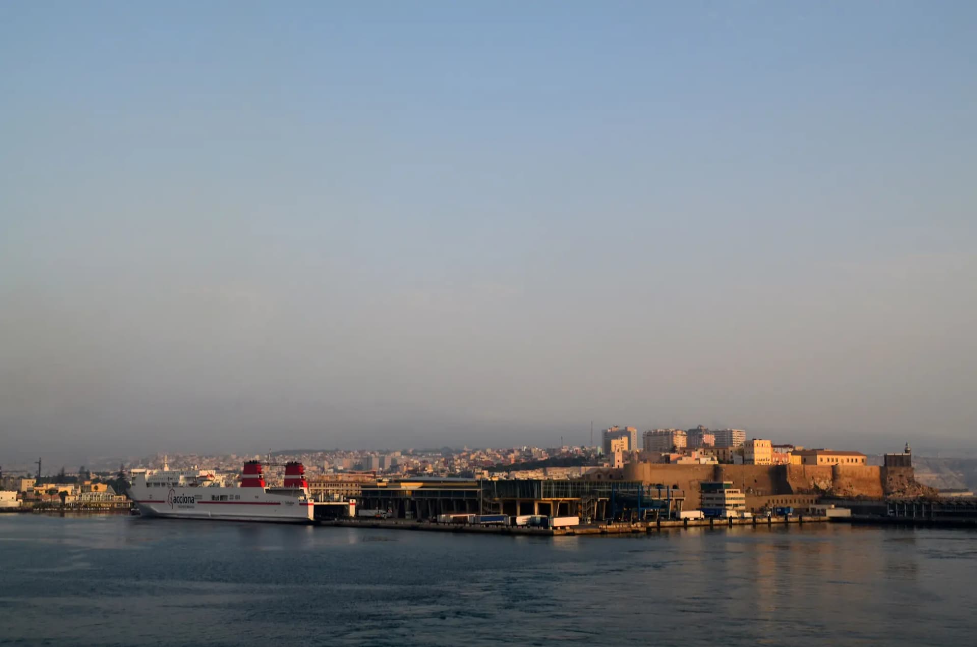 Puerto de Melilla con un ferri atracado y la ciudad al fondo a última hora de la tarde