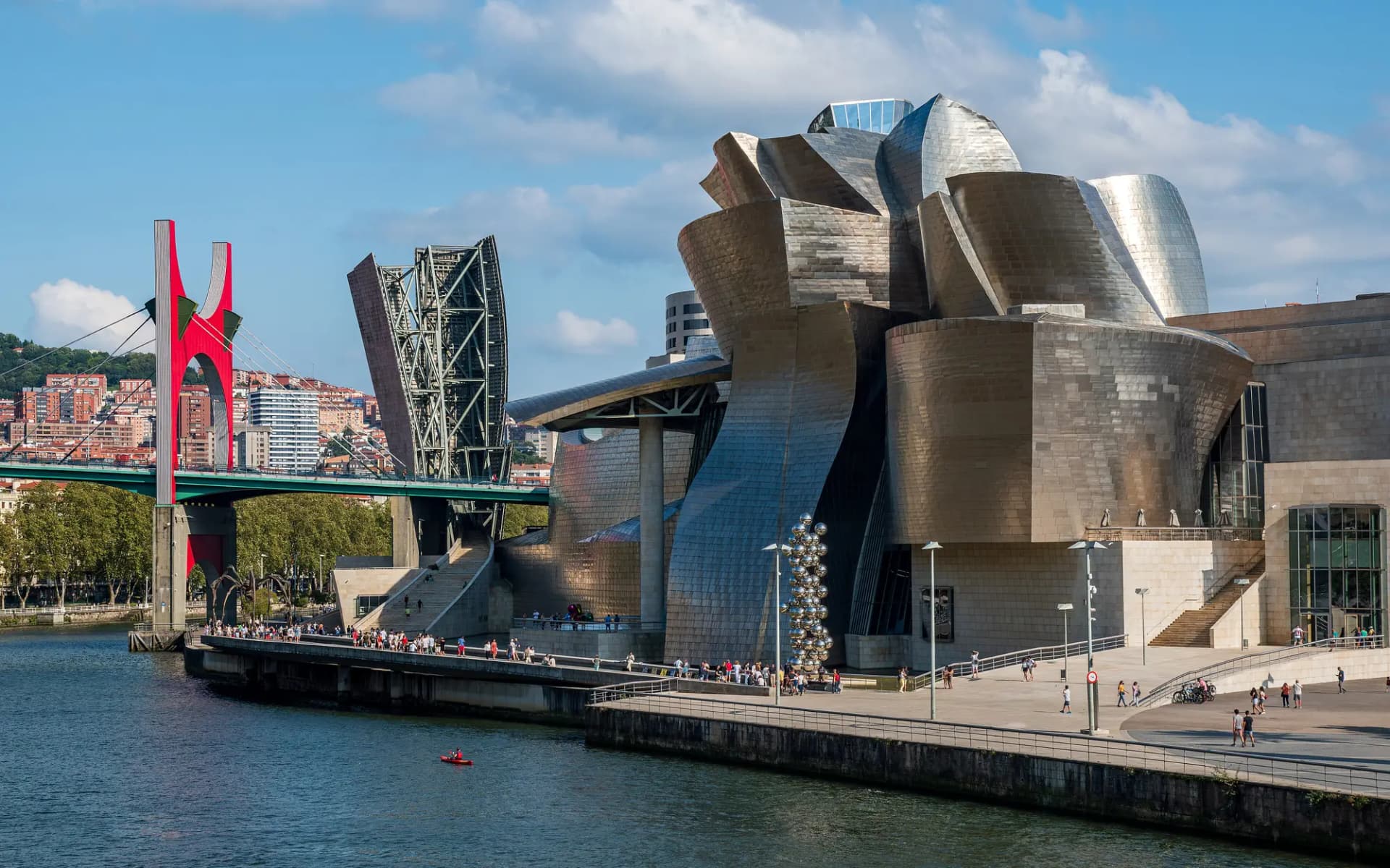 El Museo Guggenheim junto a la ría de Bilbao, con el puente de La Salve y su arco rojo a la izquierda
