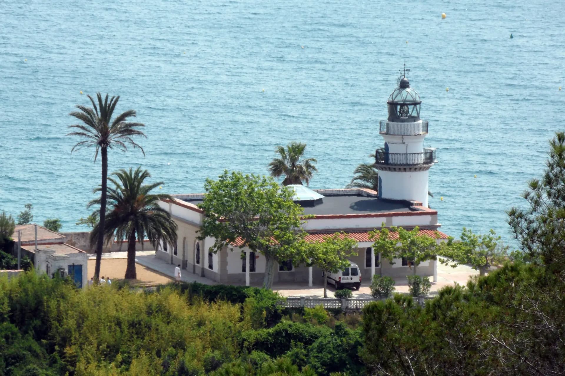 Faro de Calella sobre el cabo Capaspre, entre palmeras y con el mar al fondo