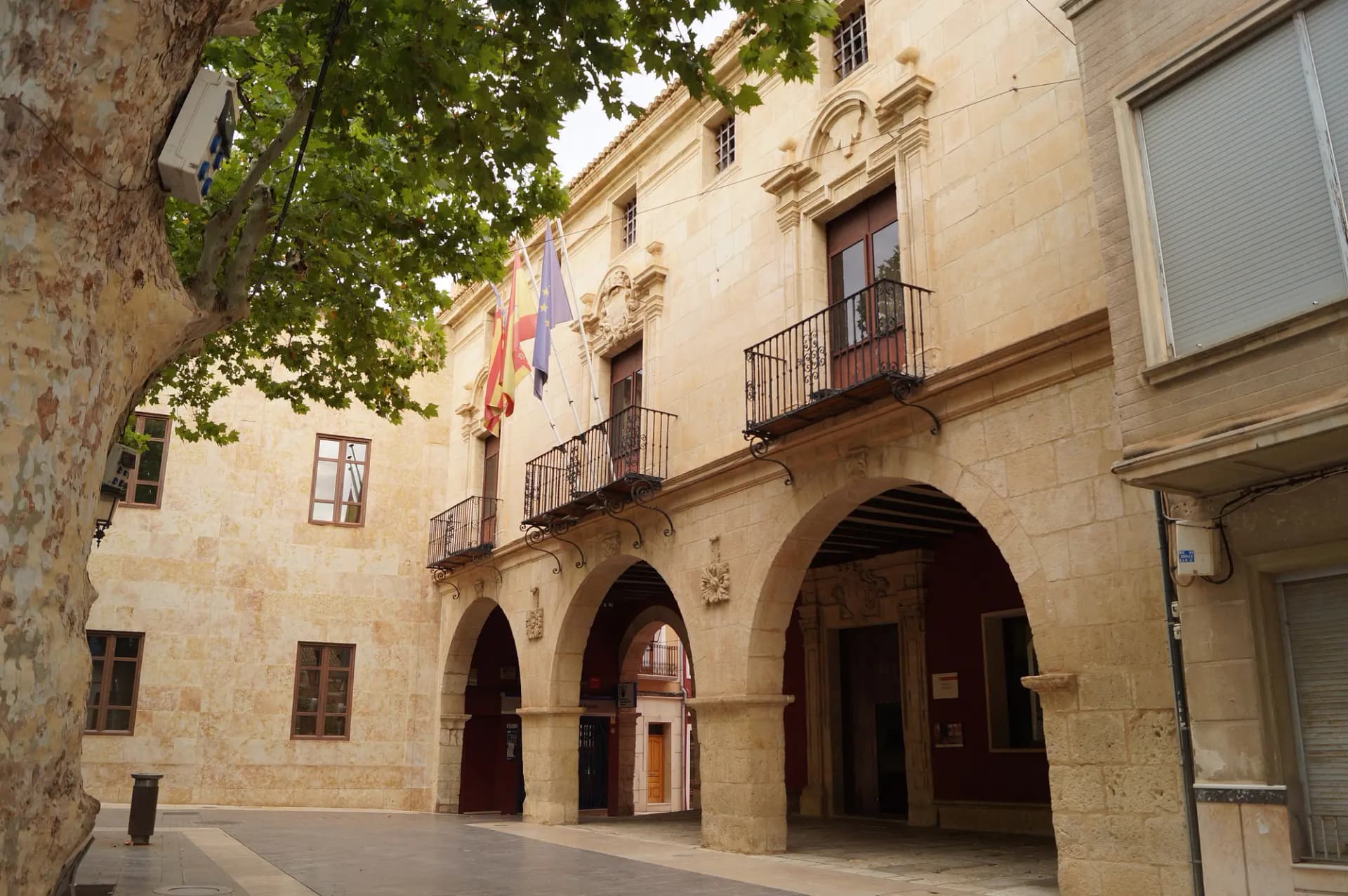 Edificio histórico del Ayuntamiento de Aspe, de piedra, con soportales de arcos y balcones